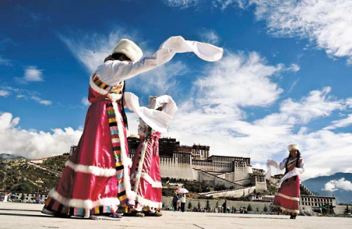 People in colorful Tibetan costumes pictured in front of the Potala Palace in Lhasa, capital of the Tibet autonomous region, in July. [PHURBU TASHI / XINHUA] 