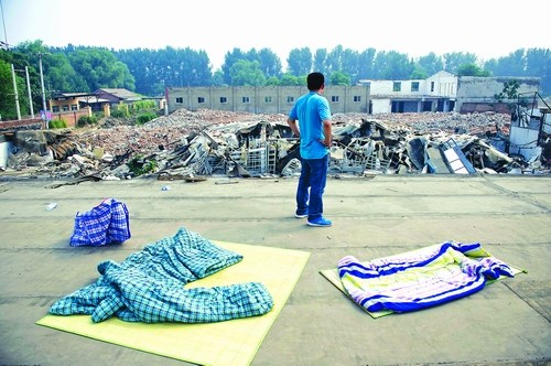 A worker stands on a roof of a dormitory, overlooking the demolished car showroom in Haidian district Thursday. Photo: Li Hao/GT 