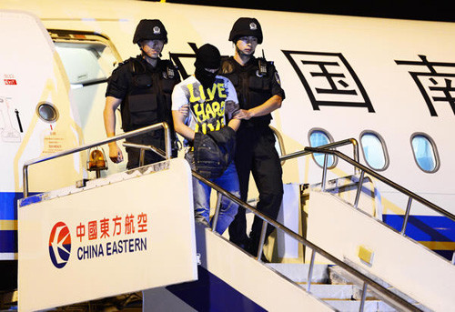 Xiong Yi, a prime suspect in a hoax bomb warning that caused the division of a domestic flight on Aug 30, was escorted by police from Dongguan, Guangdong province, to a detention center in Wuhan, Hubei province, on Sept 2, 2012. [Zhou Guoqiang / China Daily]