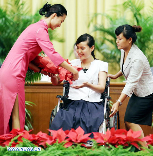 Zhanglili (C) receives flowers at a seminar on her story held at the Great Hall of the People in Beijing, China, Sept. 4, 2012. On May 8, Zhang saved two students from an onrushing bus in northeast China's Heilongjiang province. The 29-year-old teacher at the No. 19 Middle School in the city of Jiamusi, was crossing a road outside the school's main gate when she saw the two students standing in the way of the bus. She successfully pushed the students out of harm's way, but was unable to avoid the bus herself and lost her legs in the accident. (Xinhua/Yao Dawei)