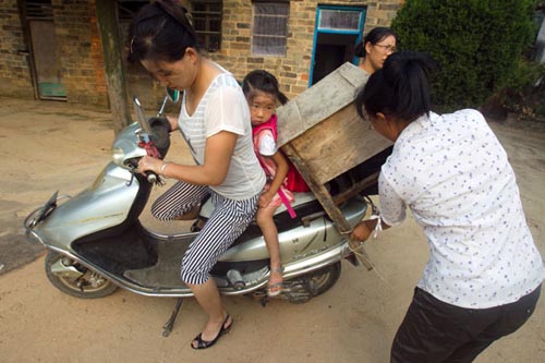 Two fellow villagers help Lu Siling and her mother unload a borrowed table on Saturday at a primary school in Shunhe township in Macheng, Hubei province. Yuan Liyang / Changjiang Times