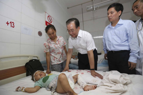 Chinese Premier Wen Jiabao (third R) visits an injured child at Yiliang County People's Hospital, Zhaotong city of Yunnan province, Sept 8, 2012. Wen arrived in the quake-hit areas in Zhaotong city on Saturday to direct the rescue work. Two quakes measuring 5.7 and 5.6 on the Richter scale hit a border area near Yiliang in Yunnan and Weining county in Guizhou province Friday, respectively. So far 80 people have been confirmed dead. [Photo/Xinhua]