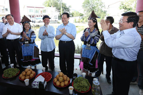 Zhou Yongkang (C), a member of the Standing Committee of the Political Bureau of the Communist Party of China Central Committee and secretary of the Committee of Political and Legislative Affairs of the CPC Central Committee, chats with people of ethnic m