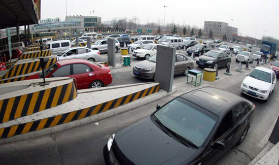 Cars wait in lines to pass a highway tollgate in Beijing on Jan 28. (Photo for China Daily)