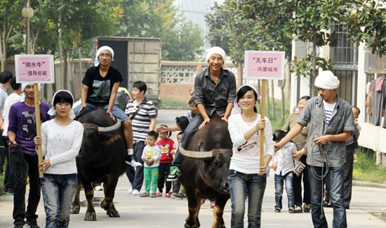 College students in Hefei, Anhui province, ride on buffaloes to promote awareness for World Car Free Day on Saturday. (Photo for China Daily)