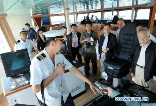 Sui Yiyong (L, front), captain of the comprehensive research vessel, the Kexue (Science), makes introduction to visitors in Qingdao, east China's Shandong Province, Sept. 29, 2012. The 99.6-meter-long and 17.8-meter wide ship was put into service on Saturday. Powered by a podded electric propulsion system, the Kexue consumes less power, creates less noise and vibration, and is able to move at continuously varying speeds of up to 15 knots. (Xinhua/Li Ziheng)