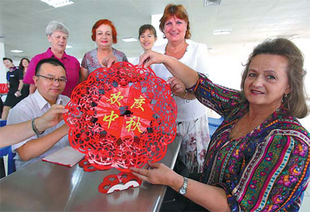 A Russian woman, who works at Tianwan Nuclear Power Plant at Lianyungang, Jiangsu province, displays her paper-cutting during a party to celebrate the Mid-Autumn Festival on Sept 26. Wang Jianmin / for China Daily