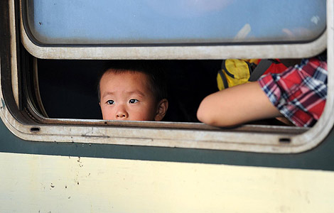 A boy looks out through a window of a train before the start of a nationwide eight days break to celebrate China's Mid-Autumn festival and National Day at Nanchang train station, Jiangxi province, September 29, 2012. [Photo/Xinhua]