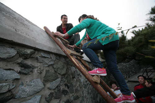 The driver of an illegal taxi sits on a wall to attract customers, while a tourist climbs a ladder to take the illegal taxi waiting on the other side of the wall near the Xianglu Peak in Xiangshan Mountain Forest Park in Beijing in October 2011. After rea