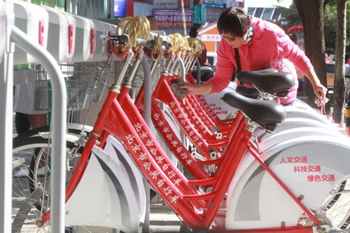 A woman inspects bikes at a rental station in Beijing. Fu Ding / for China Daily 