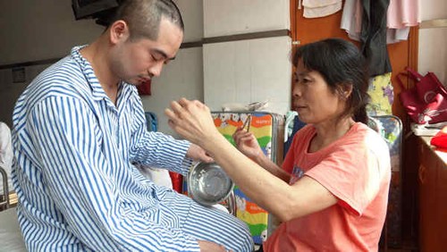 Zhang Tingzhen, 25, an employee of Taiwan company Foxconn, is fed by his mother at the Shenzhen No 2 People's Hospital on Thursday. Zhang had nearly half of his brain surgically removed after surviving an electric shock at a Foxconn plant. He has lost all