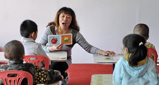 Zhang Tielian teaches hearing-impaired children during a speech training class, Oct 12, 2012. [Photo/Xinhua]