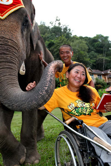 Fan Meng and his mother have a close encounter with an elephant in a park at Xishuangbanna, a popular tourism destination in Yunnan province, on Sunday. Dai Zhenhua / for China Daily 