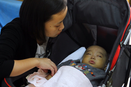 Luo Dan, a mother involved in a liver-swap surgery, takes care of her son on Monday at the General Hospital of the Armed Police Forces in Beijing. The boy received a liver transplant from another woman. Zou Hong / China Daily 