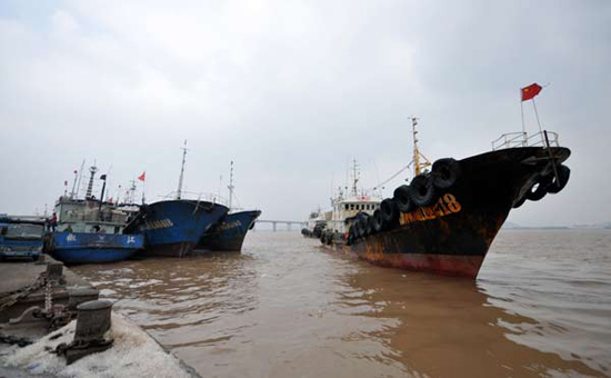 A fisherman fastens the rope that ties his boat to the port of Haimen in Taizhou, Zhejiang province, Oct 17, 2012. [Jia Ce/Asianewsphot] 