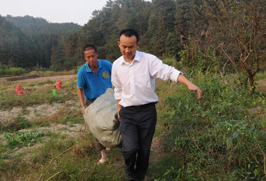 Xing Lei helps a villager with farm work, Oct 12, 2012. [Photo/Xinhua]