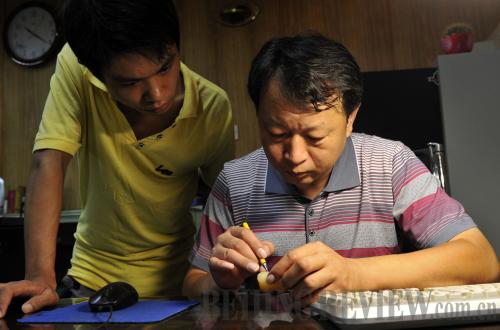 DEDICATED MENTOR: Lang Xiaofeng shows his apprentice how to carve a jade stone at his studio in Beijing (SHI GANG) 