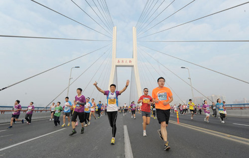 Runners pass the Nanpu Bridge in last year's Shanghai International Marathon. [Photo by Cao Zichen/For China Daily]