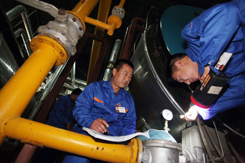 Workers perform a final round of tests on heating pipes and equipment in a boiler room in Beijing on Tuesday. Zhang Yujun / for China Daily