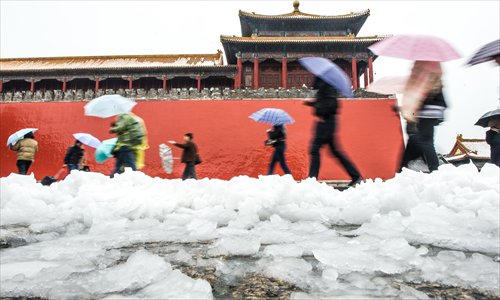 People try to control their umbrellas in the wind as they pass by the south gate of the Forbbiden City Sunday at midday. Photo: Li Hao/GT 