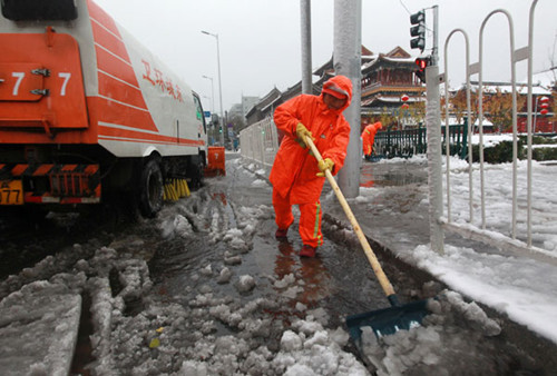 A sanitation worker shovels snow near the Yonghegong Lama Temple in Beijing on Sunday. Cui Meng / China Daily