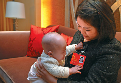 Luo Wei, a delegate to the Party congress from Sichuan province, shares a moment with her 5-month-old daughter in a hotel room in Beijing on Saturday evening. Yin Gang / for China Daily