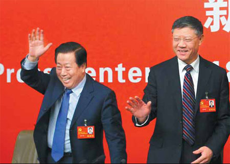 Jiang Weixin (right), minister of housing and urban-rural development, and Zhou Shengxian, minister of environmental protection, wave to reporters at a news conference during the Party congress in Beijing on Monday. Zou Hong / China Daily 