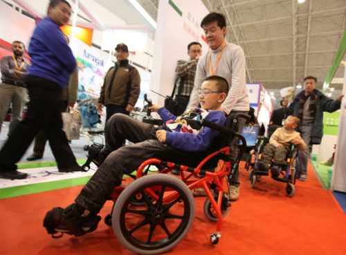 A physically disabled child tries a new type of wheelchair at the Care and Rehabilitation Expo China 2012 in Beijing on Thursday. WANG JING / CHINA DAILY