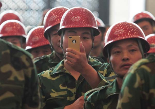 A migrant worker takes photos with his cellphone at the opening of an art show featuring his peers in Beijing. The use of smartphones is increasing among young migrant workers. Provided to China Daily 