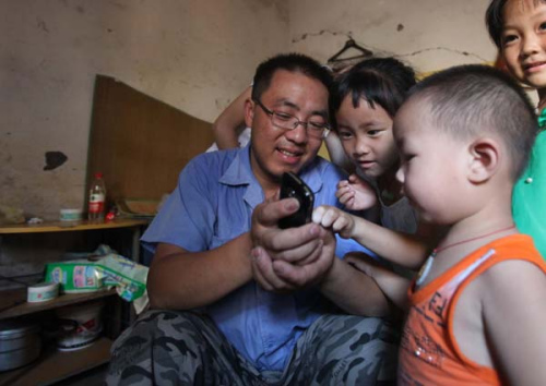 Bao Dayou, 34, a migrant worker from Anhui province, and his children play with his mobile phone at home.  