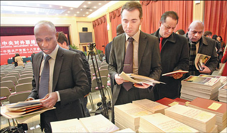 Foreign diplomats take pamphlets on the 18th National Congress of the Communist Party of China ahead of an event organized by the International Department of the CPC Central Committee in Beijing on Tuesday. Zhang Wei / China Daily 