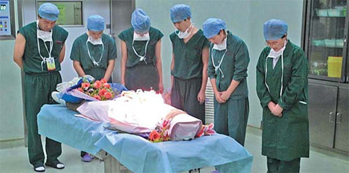 Nurses pay homage to Wu Huajing, who agreed to donate her organs after a traffic accident from which she later died, before transplant surgery on Thursday evening at the General Hospital of Guangzhou Military Command in Guangdong province. [Photo/China Daily] 