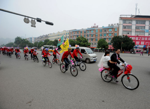 through Baise city, Guangxi province, on Nov 25, 2012. Since National Day on Oct 1, bicycle weddings have become popular in the old revolutionary city. Young people have opted for two wheels over four for environmental reasons and the added romance of lov