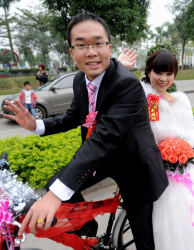 A couple poses during their bicycle wedding in Baise city, Guangxi province on Nov 25, 2012. Since National Day on Oct 1, bicycle weddings have become popular in the old revolutionary city. Young people have opted for two wheels over four for environmental reasons and the added romance of love-on-a-bike. [Photo by Luo Zhiken/Asianewsphoto]