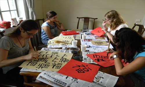 Westerners in a calligraphy class practice drawing the Chinese character fu (good luck).  