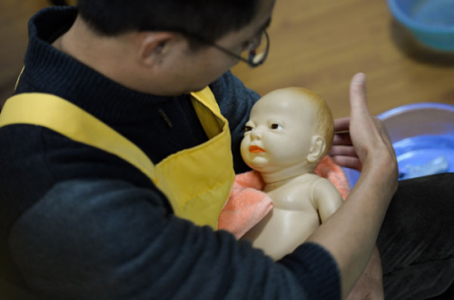 Li Dabin trains with a toy baby on Dec 1, 2012. Li, a former college teacher with a master's degree, gave up his former job and decided to become a maternity matron. He attends training in Changsha, Central China's Hunan province and has set up his own domestic service company in Kunming, Yunnan province. A maternity matron encompasses the role of nanny, nurse, cook and pre-school teacher and thus the salary can be more than 6,000 yuan ($963) in big cities such as Beijing and Shanghai. During peaks in birthrates, the demand for the service usually exceeds supply. [Photo/Xinhua]