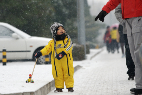 A boy and his mother play in the snow on Wednesday in Beijing. More snow is expected to hit the capital on Thursday. [Photo by WEI XIAOHAO / CHINA DAILY]