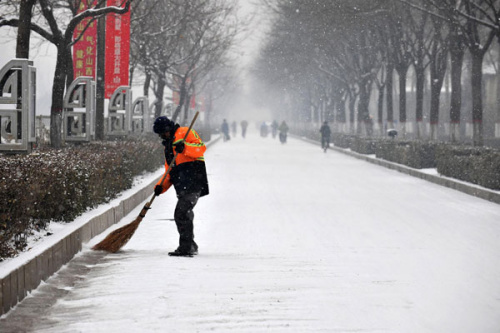 A cleaner sweeps snow from the road in Taiyuan, Shanxi province after the city was covered on Dec 13. [Photo/Xinhua]