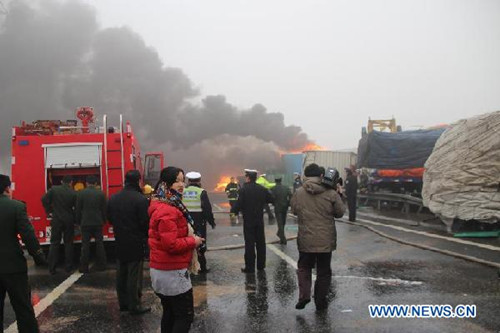 Rescuers and working staff work at the accident site after a pile-up involving over 20 vehicles happened on a snow-coated section of an expressway in Pingyin County of Jinan, capital of east China's Shandong Province, Dec. 14, 2012. [Xinhua]