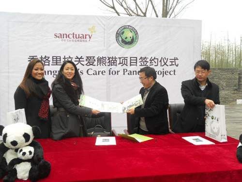 Zhang Hemin (right), chief of the administrative bureau of the Wolong National Nature Reserve, presents a postage-stamp album to representatives of Shangri-La Hotels and Resorts on Saturday after they signed a contract in which Shangri-La agreed to plant more than 9,000 bamboo trees in the Dujiangyan Giant Panda Rescue and Disease Control Center in Sichuan province. [Photo/chinadaily.com.cn]