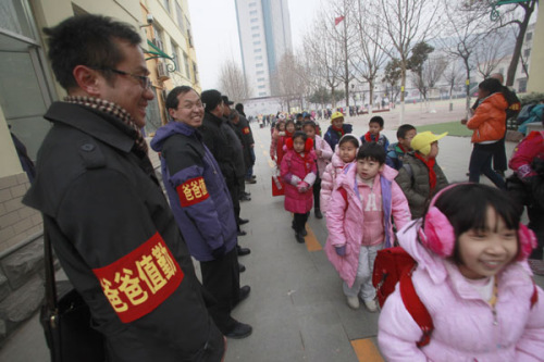 Fathers stand at the shcool gate of Shungeng Primary School to protect students in Jinan, Shandong province, Dec 20. The school set up the Guards of Fathers to maintain school security. [Photo/Asianewsphoto]