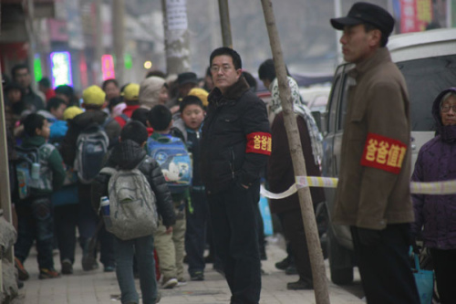 Fathers stand at the shcool gate of Shungeng Primary School to protect students in Jinan, Shandong province, Dec 20. The school set up the Guards of Fathers to maintain school security. [Photo/Asianewsphoto]