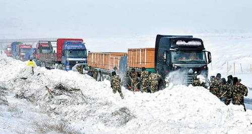 Soldiers in the Xinjiang Uygur autonomous region clear the road for stranded vehicles on Sunday. A cold snap is causing traffic delays in parts of China. Zou Yi / For China Daily 