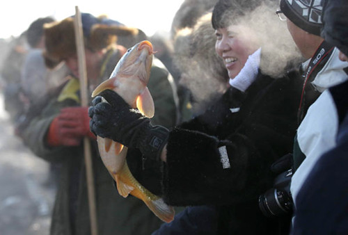 A wriggling fish is proudly displayed during a traditional winter fishing event on the frozen Chagan Lake, Jilin province, on Thursday. ZHAO BIN / FOR CHINA DAILY