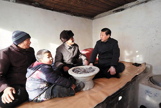 Party chief Xi Jinping chats with farmer Tang Rongbin as they sit on a kang, a heatable brick bed, at Tangs village home in Hebei province, on Saturday.[Lan Hongguang / Xinhua] 