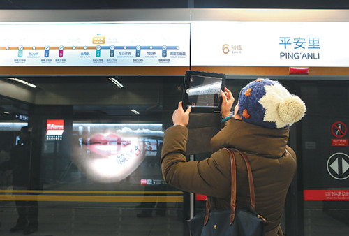 A passenger takes photos at Ping'anli Station in Beijing on Sunday. Four new subway routes went into operation, increasing the length of the capital city's subway to 442 kilometers. [Photo/Xinhua]