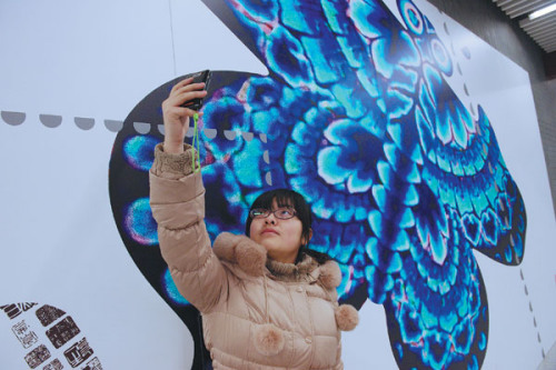 A woman takes photos at Nanluoguxiang Station on Line 6 on Sunday. The station's decoration features the traditional folk art of Beijing. Wei Xiaohao / for China Daily