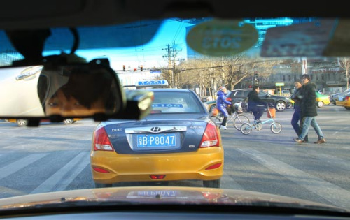 Cars brake on the yellow light at a Beijing intersection on Thursday. A new traffic regulation that aims to stop drivers from running yellow lights has caused an outcry, with many Internet users saying it will lead to more accidents. [Photo by Zou Hong / China Daily]