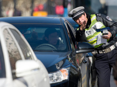 A Hangzhou police officer fines a driver for a traffic violation on Tuesday. [Provided to China Daily]