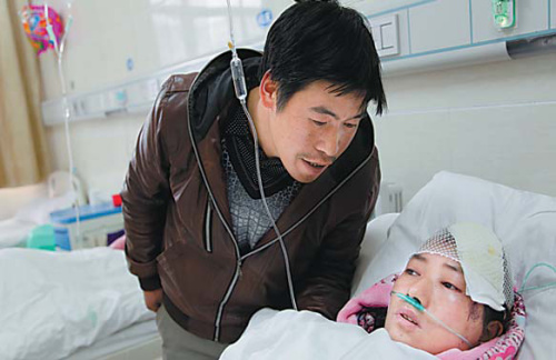 Wang Yinfa talks with his wife, An Qingduan, who was injured in a deadly landslide in Zhenxiong, Yunnan province, at a hospital in the county on Sunday. The landslide, which occurred on Friday, killed 46 people and injured two. ZHANG GUANGYU / FOR CHINA DAILY